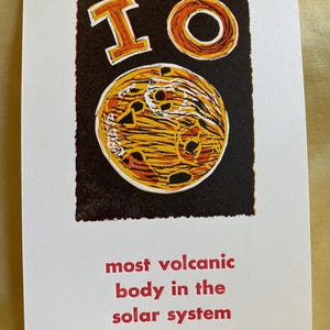 Puede incluir: Una impresión en negro y naranja de la luna Io, con el texto "most volcanic body in the solar system".