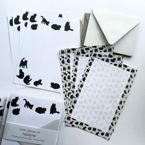 May include: A stationery set featuring white grid paper with black cat silhouettes, gray envelopes, and sheets with a repeating cat pattern. The packaging includes the text: LETTER WRITING SET, robayre, 8 Sheets of Stationery Paper, 4 A2 envelopes.