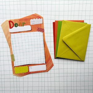 May include: A stack of orange stationery sheets featuring the word Dear, a grid-patterned writing area, and fields for Location, Date, and PS, alongside a stack of envelopes in shades of red, orange, lime green, and yellow.