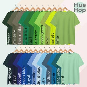 May include: A collection of 20 t-shirts in various shades of green and blue. The shirts are arranged in two rows, with the top row featuring shades of green and the bottom row featuring shades of blue. Each shirt has a different color name printed below it, such as "forest", "military", "ant. irish", "turf", "electric", "neon green", "kiwi", "safety", "lime", "midnight", "navy", "cobalt", "neon blue", "royal", "carolina", "light blue", "sky", "indigio", "saphir", "ant. jade", and "mint". The text "Hue Hop" is printed in the top right corner of the image.