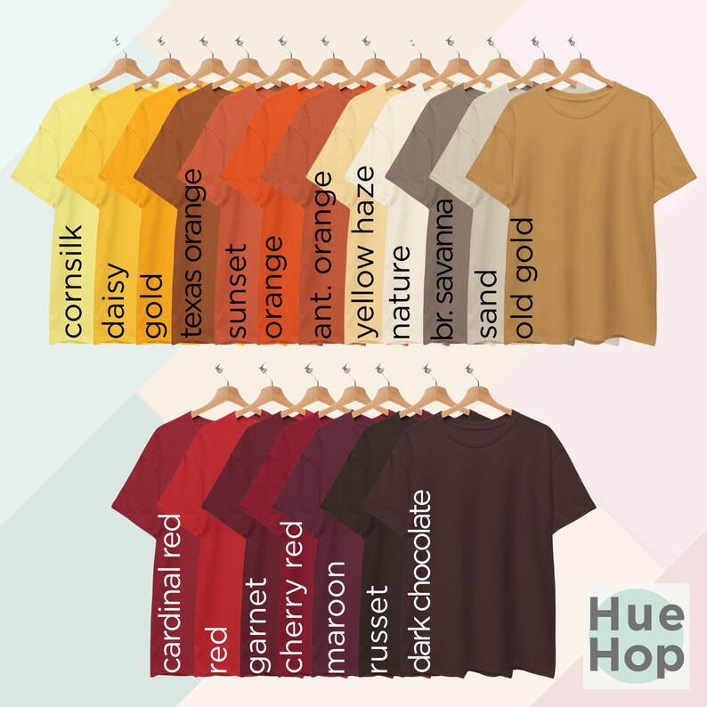 May include: A collection of 20 t-shirts in various shades of orange, red, and brown, hanging on hangers. The t-shirts are labeled with color names like "cornsilk", "daisy", "gold", "texas orange", "sunset", "orange", "ant. orange", "yellow haze", "nature", "br. savanna", "sand", "old gold", "cardinal red", "red", "garnet", "cherry red", "maroon", "russet", "dark chocolate", and "Hue Hop".