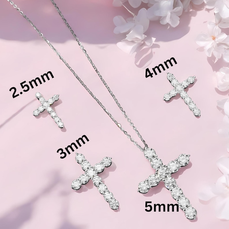 May include: A silver-toned jewelry set featuring cross pendants and earrings. The set includes a necklace with a 5mm cross pendant, a pair of 2.5mm earrings, and two additional crosses measuring 3mm and 4mm. The jewelry is set against a pink background.