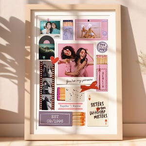May include: A framed collage featuring photos, illustrations, and text. The images include photos of people, matchboxes, and a film strip. Text includes "1996", "You're my person", "Together Forever", "Sisters from Different Misters", and "EST 09/1996". The frame is a light beige color.