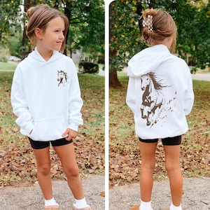 Tween girl modeling a youth equestrian hoodie with horse design, smiling and looking to the side.