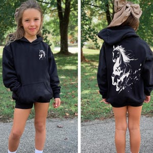Teen girl in a cozy horse lover sweatshirt, showing the back graphic of a galloping horse.