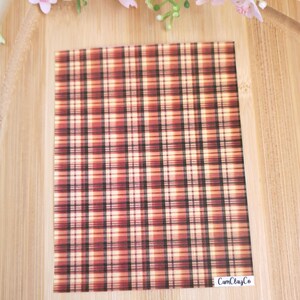 Peut inclure: Une feuille de vinyle avec un motif à carreaux rouge, noir et crème. La feuille a un effet aquarelle subtil et est étiquetée "CamClayCo".