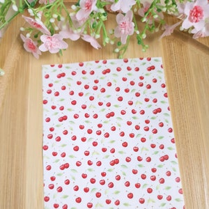 Puede incluir: Fondo blanco con un patrón repetido de cerezas rojas con hojas verdes. El texto "CamClayCo" está en la esquina inferior derecha.