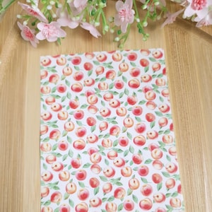 Peut inclure: Une feuille de papier blanche avec un motif répétitif de pêches roses et de feuilles vertes. Le texte "CamClayCo" est dans le coin inférieur droit.