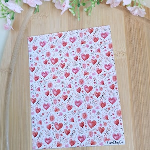 Peut inclure: Une feuille rectangulaire avec un motif répété de coeurs rouges et de roses roses sur fond blanc. Le motif comprend de petites feuilles vertes. Le texte "CamClayCo" est visible.
