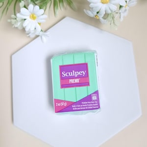 Peut inclure: Un bloc d'argile à cuire au four Sculpey Premo de 57 grammes (2 onces) de couleur vert clair. L'emballage porte le nom de la marque Sculpey et le nom du produit Premo en texte violet.