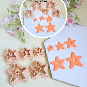 Peut inclure: Un ensemble d'emporte-pièces en forme d'étoile de couleur pêche de différentes tailles, dotés d'un embout central pour créer des trous, avec des étoiles découpées. Le texte "Également disponible sans trou" est visible dans l'encart.