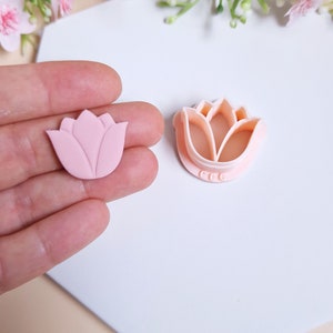Op de afbeelding: Een roze polymer clay tulpenbloem en een plastic tulpenkoekjesvormpje. Het koekjesvormpje heeft de letters "CCC" op de onderkant.