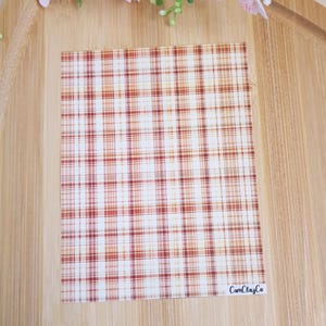 Peut inclure: Une feuille de papier à motifs blancs avec un motif à carreaux rouge et orange. Le papier a un effet aquarelle subtil et le texte "CamClayCo" est imprimé dans le coin inférieur droit.