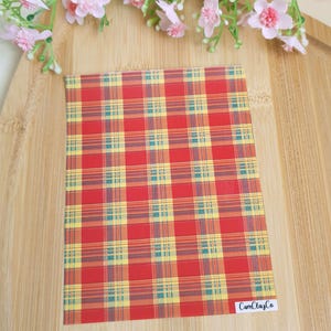May include: A rectangular sheet with a red plaid pattern, featuring yellow and teal lines. The sheet is on a wooden surface, with pink flowers in the background. The text "CamClayCo" is visible in the bottom right corner.