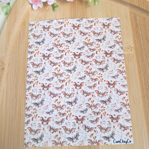 Puede incluir: Una hoja rectangular con un patrón repetido de murciélagos, hojas y elementos florales en tonos marrón, gris y naranja sobre un fondo blanco. El diseño es adecuado para manualidades o fines decorativos. El texto "CamClayCo" es visible.