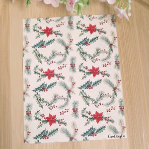 Peut inclure: Une feuille de papier blanche avec un motif répété de fleurs de poinsettia rouges, de feuilles de houx vertes et de baies rouges. Le papier porte le texte "CamClayCo" dans le coin inférieur droit.