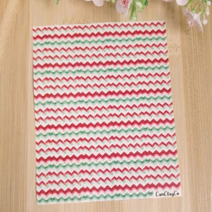 Peut inclure: Feuille de vinyle à motif chevron rouge et vert. La feuille a un fond blanc avec des rayures chevron rouges et vertes. La feuille mesure environ 30 cm sur 30 cm. Le texte "CamClayCo" est dans le coin inférieur droit de la feuille.