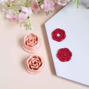 May include: Two pink and two red rose-shaped fondant cutters. The cutters are made of plastic and have a detailed rose design.