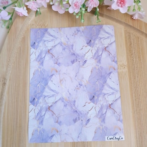 May include: A sheet of purple and white marble patterned paper with gold accents. The paper has a subtle watercolor effect and is perfect for crafting projects. The paper is labeled "CamClayCo."