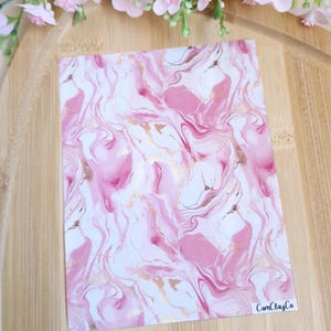 May include: Pink and gold marbled paper with a white background. The paper has a swirling pattern and is perfect for crafting projects. The paper is made by CamClayCo.