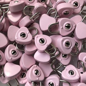 May include: A pile of pink heart-shaped padlocks with silver metal clasps. The padlocks are small and have a shiny finish.