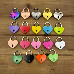 May include: A collection of heart-shaped padlocks in various colors, including iridescent, silver, gold, and vibrant hues like purple, red, and green. The locks are arranged on a wooden surface, showcasing their decorative design.