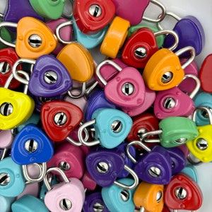 May include: A collection of colorful heart-shaped padlocks in various shades of red, pink, orange, yellow, green, blue, and purple. The padlocks are made of metal and have a shiny finish.