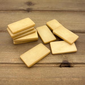 Puede incluir: Una pila de seis fichas rectangulares de madera de color marr&oacute;n claro. Las fichas est&aacute;n dispuestas en una pila con la ficha superior mirando hacia la c&aacute;mara. Las fichas son lisas y tienen un acabado ligeramente brillante.