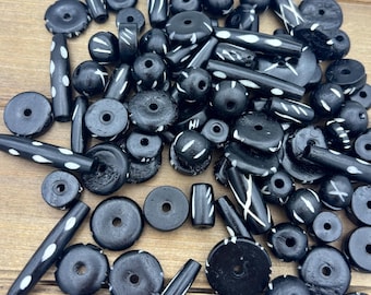 May include: A collection of black and white wooden beads with various geometric patterns. The beads are round, cylindrical, and disc-shaped.