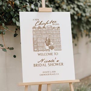 Peut inclure: Un chevalet en bois présente une affiche blanche avec du texte et des illustrations marron. L'affiche indique « A New Chapter Begins » au-dessus d'un dessin d'une femme dans une bibliothèque. Elle souhaite la bienvenue aux invités à la bridal shower de Nicole.