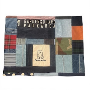 May include: A rectangular patchwork textile featuring various fabric textures including blue denim, red plaid, striped patterns, camouflage, and solid orange. A central beige panel displays a graphic of a Pomeranian dog with the text Pomeranian.