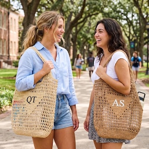 Puede incluir: Dos mujeres caminando al aire libre, cada una con un bolso tote tejido. Las bolsas son de color beige con una construcci&oacute;n de tejido abierto y presentan iniciales. Una bolsa tiene "QT" y la otra "AS". Las mujeres sonr&iacute;en y r&iacute;en.