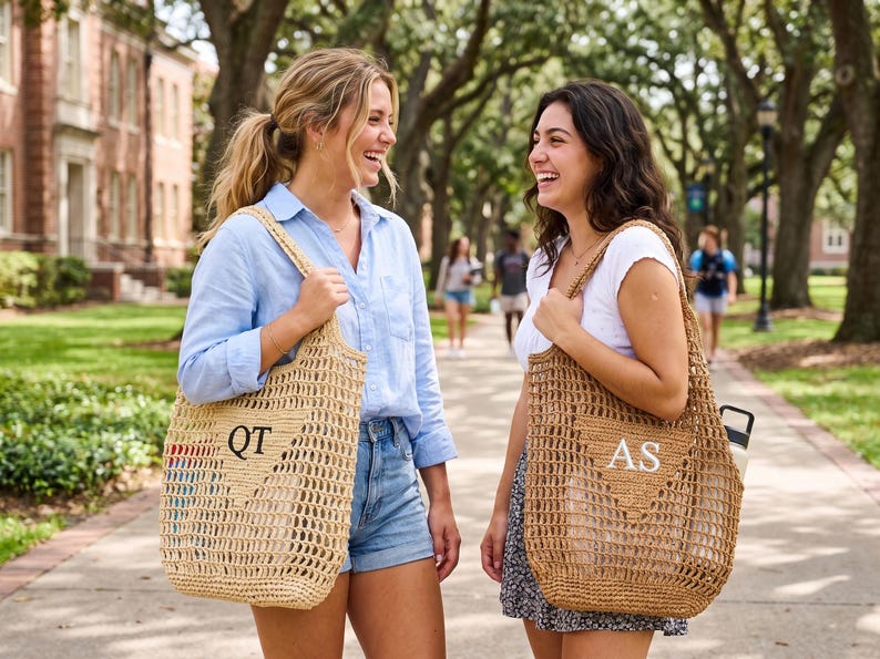 Puede incluir: Dos mujeres caminando al aire libre, cada una con un bolso tote tejido. Las bolsas son de color beige con una construcci&oacute;n de tejido abierto y presentan iniciales. Una bolsa tiene "QT" y la otra "AS". Las mujeres sonr&iacute;en y r&iacute;en.