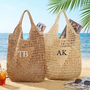 Puede incluir: Dos bolsos de mano tejidos en tonos beige y marr&oacute;n claro sobre una playa de arena. Cada bolso tiene un dise&ntilde;o de tejido abierto grande, un asa y un bolsillo con iniciales bordadas. Se ven revistas dentro de los bolsos. Gafas de sol y una bebida en primer plano.