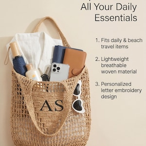 Puede incluir: Un bolso tote tejido beige con las iniciales "AS" bordadas. La bolsa contiene una camisa blanca, una cartera, un tel&eacute;fono y gafas de sol. El texto de la imagen dice "Espacioso para todos tus elementos esenciales diarios".