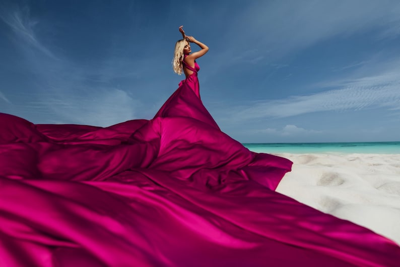 A woman in a flying dress photoshoot on the beach.