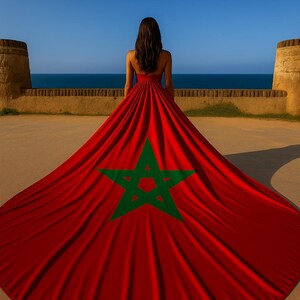 May include: A woman stands with her back to the viewer, wearing a red dress that flows into a train featuring the green star emblem of Morocco. The scene is set against a backdrop of a blue sky and ocean.