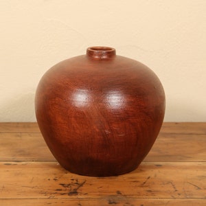 Peut inclure: Un vase en céramique brun foncé de forme ronde et bulbée. Le vase a une finition lisse et brillante.