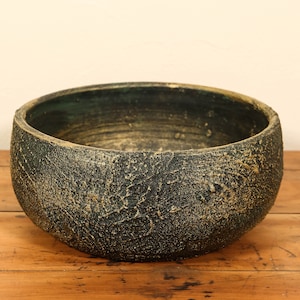 Peut inclure: Un pot en céramique vert foncé et doré avec une surface texturée.