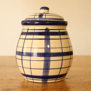 Peut inclure: Un pot en céramique blanche avec un motif à carreaux bleu et blanc. Le pot a un couvercle et est parfait pour ranger des articles de cuisine.