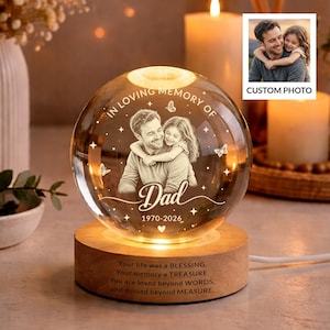 May include: A personalized memorial sphere with a photo of a father and child, the words "IN LOVING MEMORY OF Dad 1970-2026" are etched on the glass. The wooden base has the inscription: "Your life was a BLESSING. Your memory a TREASURE."