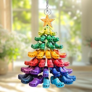 Puede incluir: Un adorno de árbol de Navidad hecho de zuecos coloridos. El árbol está dispuesto en forma triangular, con una estrella dorada en la parte superior. Los zuecos son de una gama de colores, incluyendo amarillo, verde, naranja, rojo, morado y azul.
