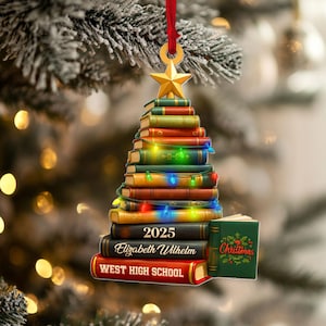 May include: A Christmas tree decoration in the shape of a stack of books, topped with a gold star and a red ribbon. The books are adorned with colourful lights and the text "2025", "Elizabeth Wilhelm", and "West High School". A small book with "Christmas" is also included.