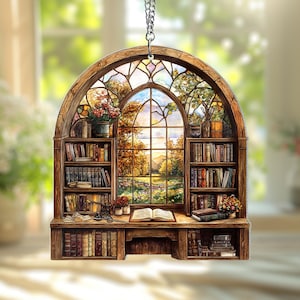 May include: A stained glass window with a view of a lush green field and a distant forest. The window is framed by two wooden bookshelves filled with books. A wooden desk with a book and other items sits below the window.
