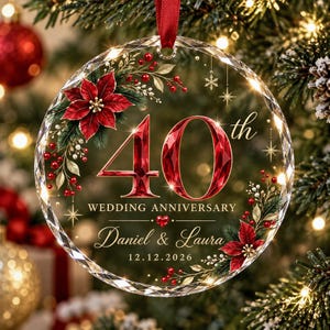 May include: A round, clear, faceted glass ornament featuring a red ribbon hanger. The design includes the text 40th WEDDING ANNIVERSARY, Daniel & Laura, and 12.12.2026. It is decorated with red poinsettia flowers, green leaves, red berries, and gold stars.