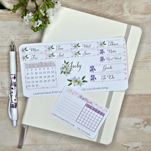 May include: A set of printable planner stickers with a floral theme. The stickers include a calendar for July, a weekly planner with days of the week, and a habit tracker. The stickers are in shades of pink, white, and purple.