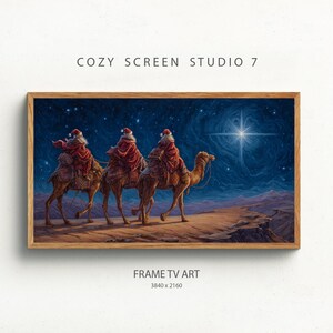 May include: A framed digital art print depicts three figures in Santa hats riding camels across a desert landscape under a starry night sky. The artwork is framed in a wooden frame and includes the text "COZY SCREEN STUDIO 7" and "FRAME TV ART".