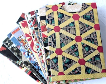 May include: A stack of decorative greeting cards with various colorful patterns. The cards feature geometric designs, floral prints, and patchwork-style motifs. The color palette includes red, gold, green, blue, and black.