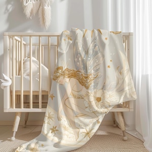 Peut inclure: Une couverture bébé de couleur crème avec une illustration de fée dorée. La fée a des ailes, de longs cheveux et tient une fleur. La couverture a un léger chatoiement et est décorée d'étoiles dorées.