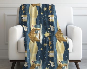 Pode incluir: Uma manta de arremesso azul e dourada com um padrão repetido da cena da natividade. A cena apresenta um estábulo de madeira, uma estrela e figuras de Maria, José e o menino Jesus.